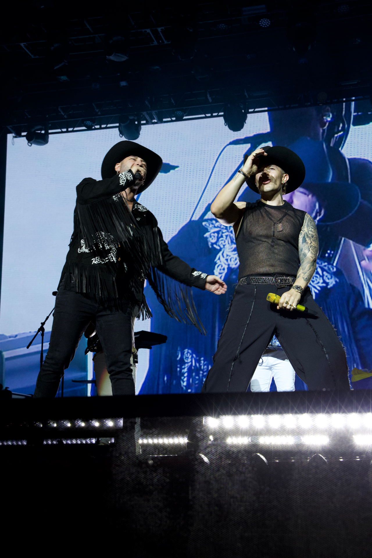 Heider Gonzalez con sombrero negro junto a otro artista en escenario
